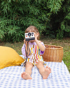 Meisje met camera in rainbow stripe overall