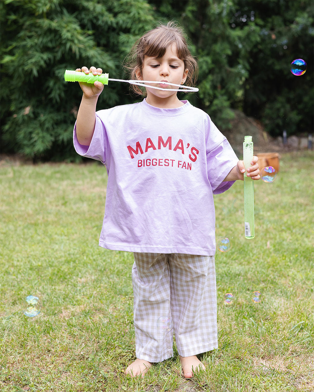 Meisje in beige gingham pants met mama's biggest fan tee