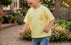Child in a yellow shirt standing in a garden with houses in the background