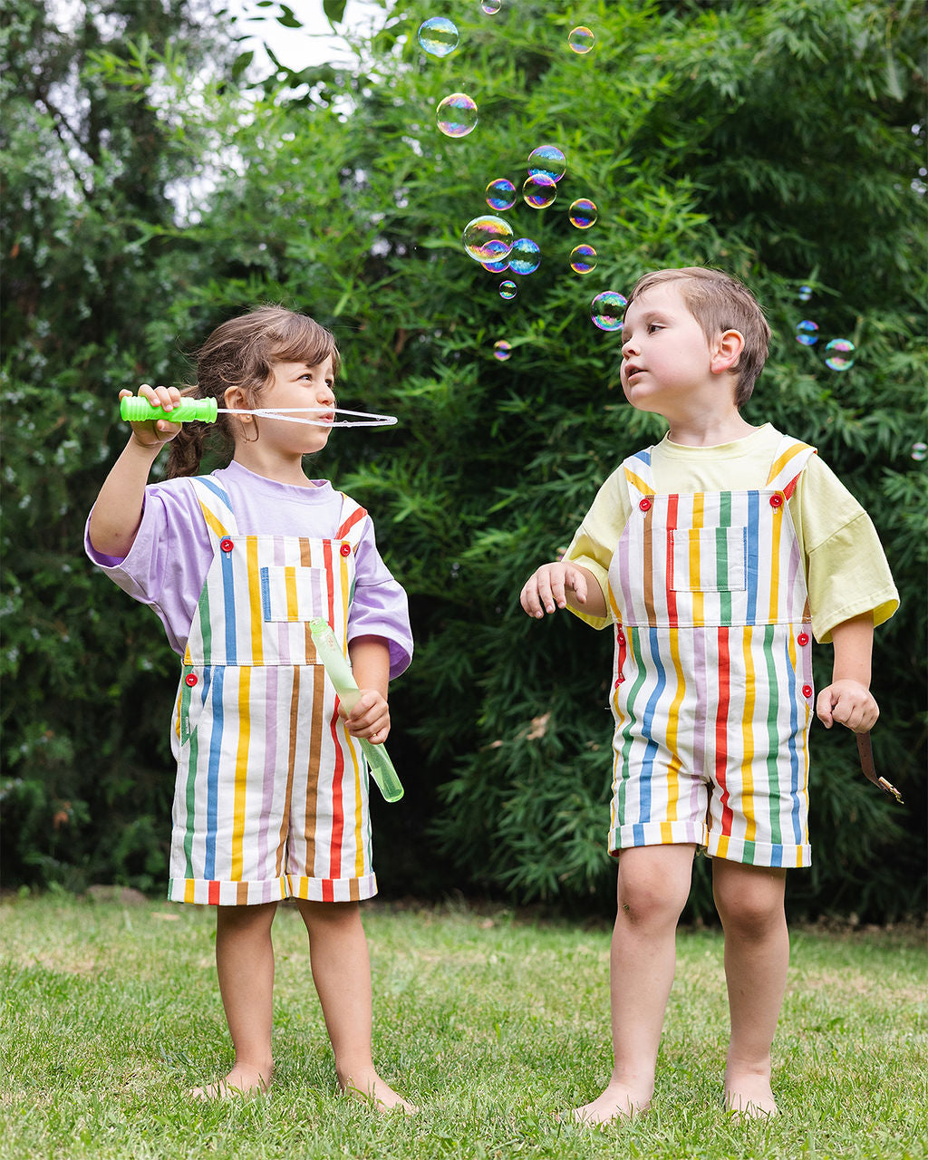 Twee kinderen in rainbow stripe overalls met bellenblaas