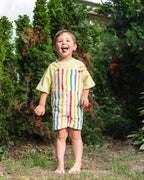 Meisje in rainbow stripe overall met lila tee