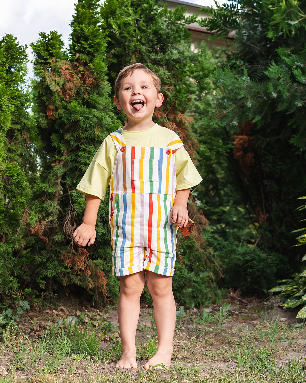 Meisje in rainbow stripe overall met lila tee