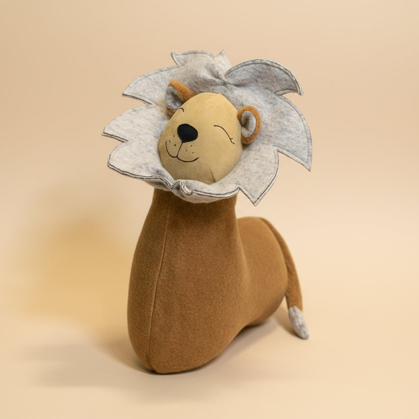 Plush toy lion with a flower-like mane on a green surface with plants in the background