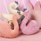 Set of plush swan toys on a pink background