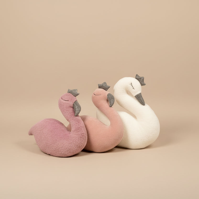 Plush toys resembling flamingos on a pink surface with decorative elements.