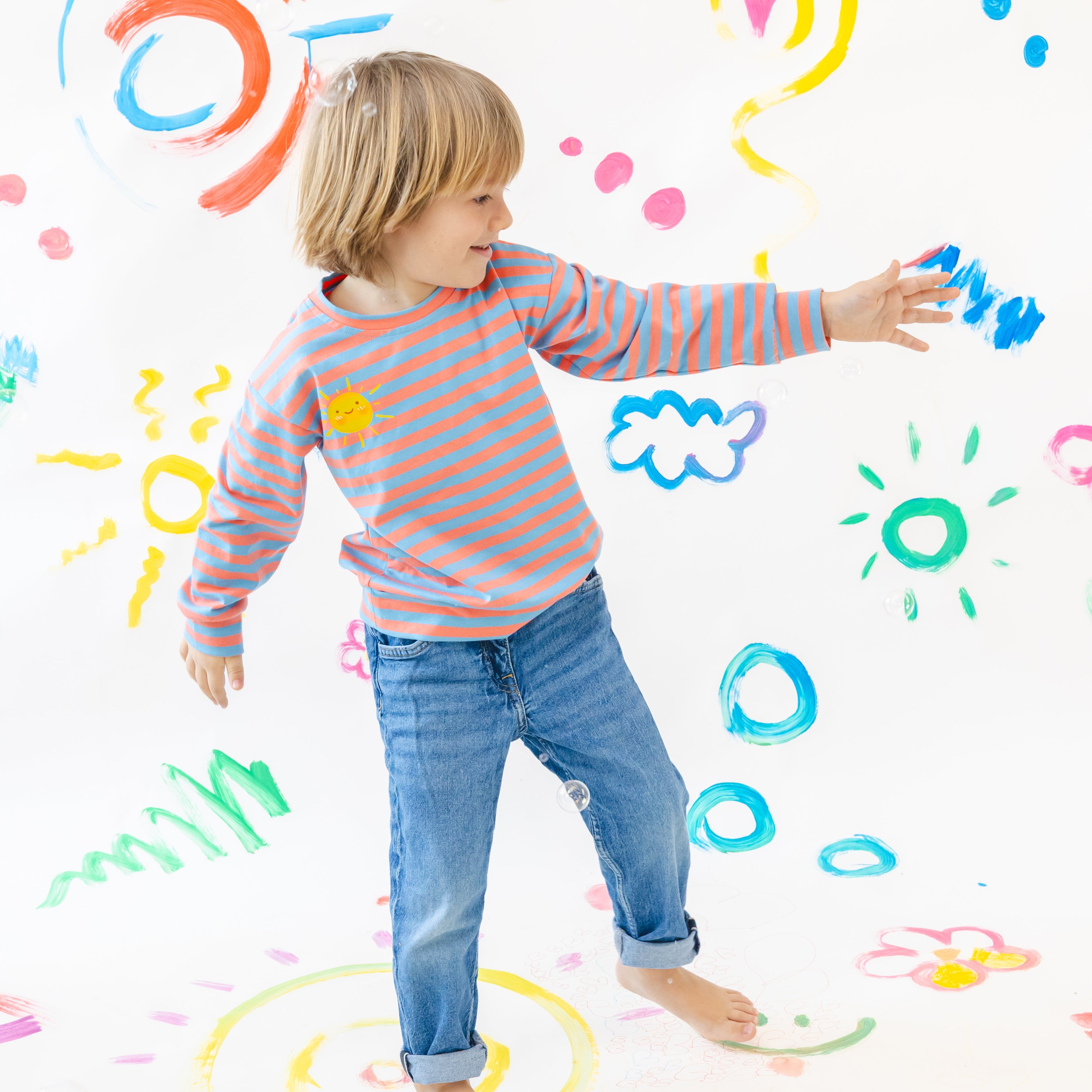 Child playing with colorful drawings on a white wall