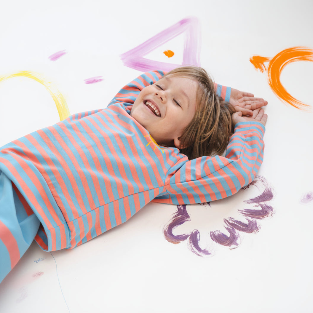Child lying on a colorful floor with painted letters and shapes