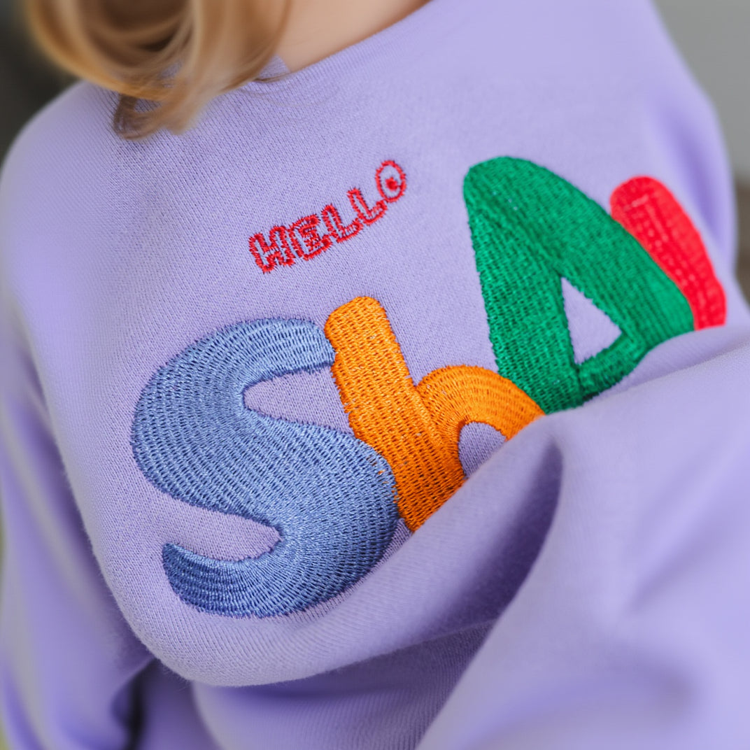 Hello Shams Original Set Soft Lilac — close-up of colorful HelloShams embroidery on lavender kids sweatshirt